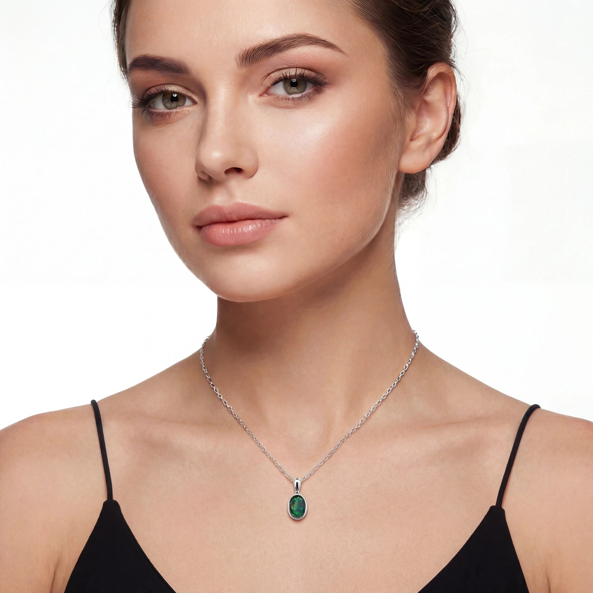 Woman wearing a silver necklace with a green pendant on a white background