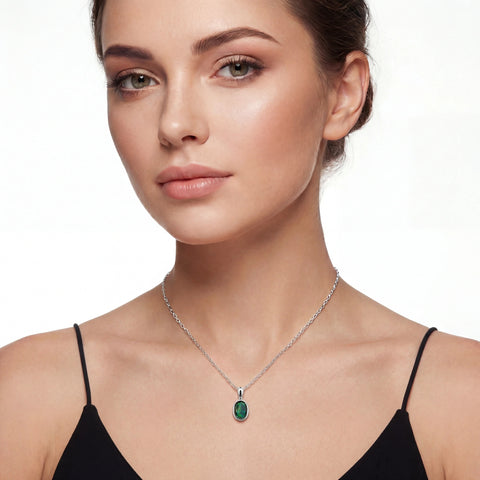 Woman wearing a silver necklace with a green pendant on a white background
