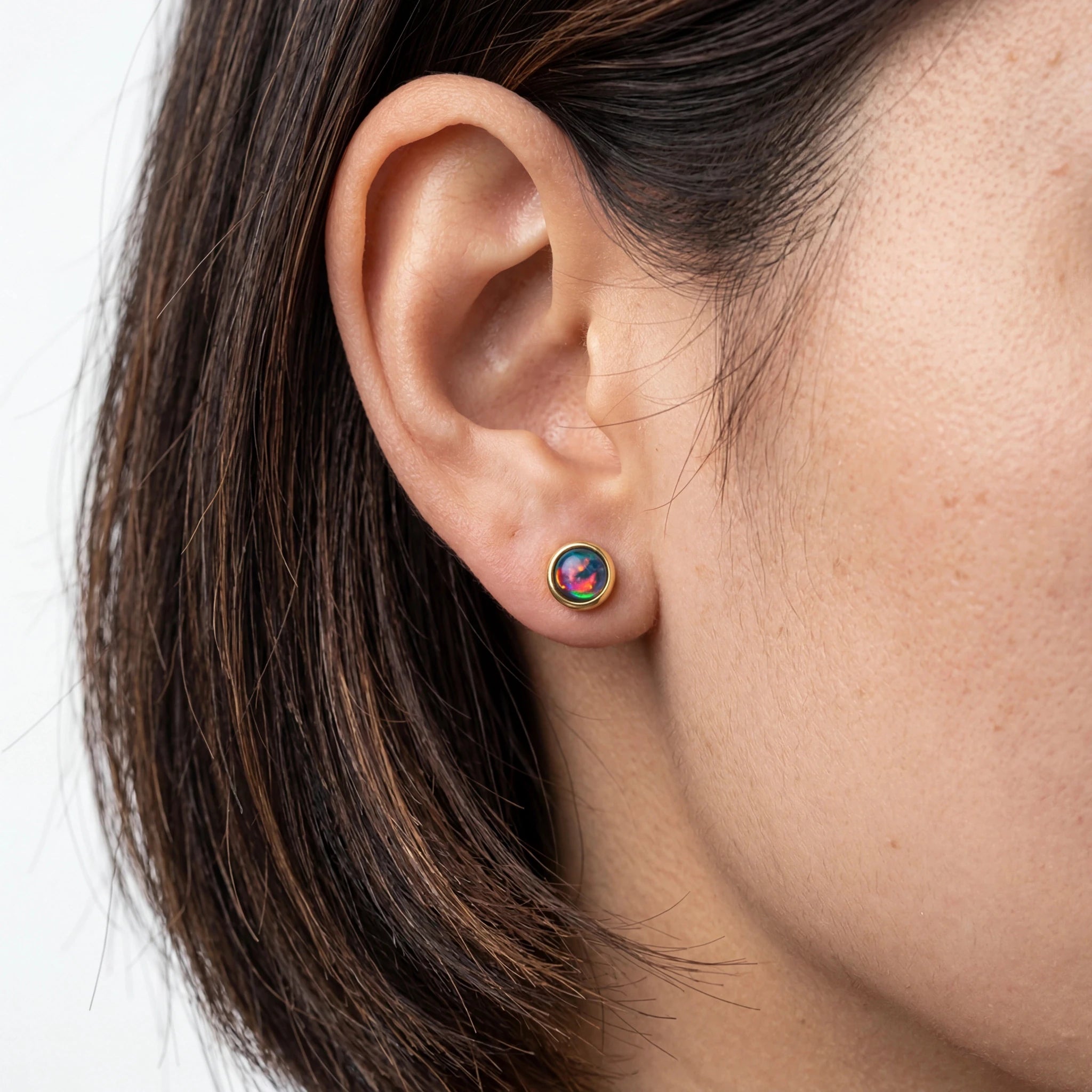 Close-up of an ear wearing a colourful earring with a neutral background