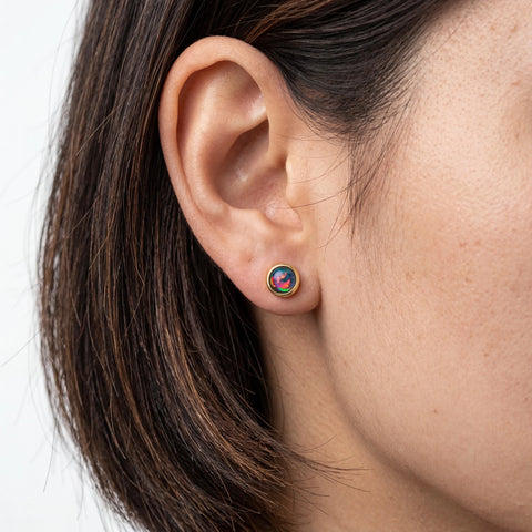 Close-up of an ear wearing a colourful earring with a neutral background