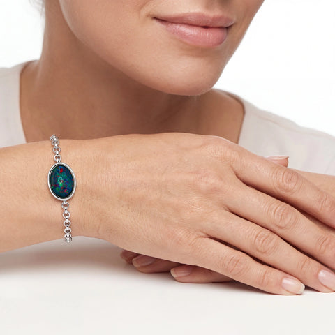 Close-up of a hand wearing a silver bracelet with a colourful gemstone on a white background