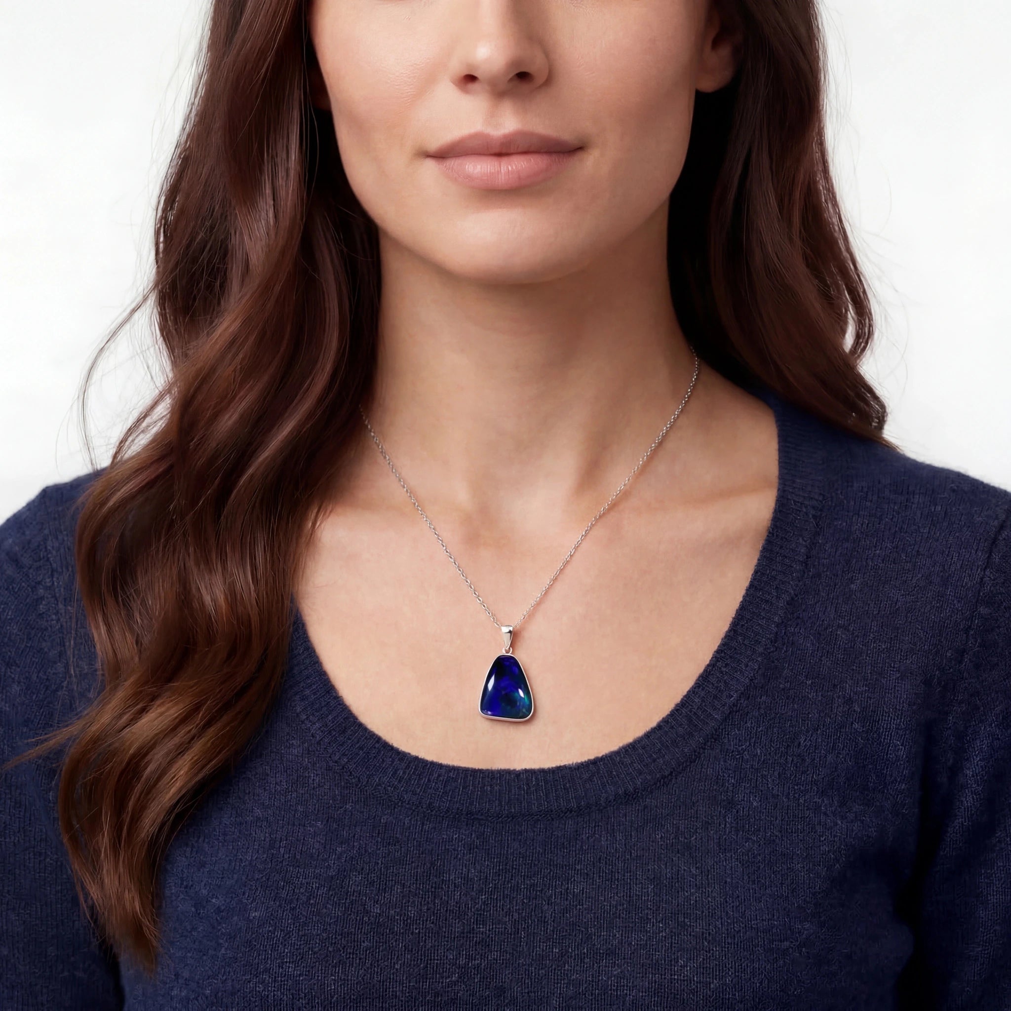 Woman wearing a necklace with a blue pendant on a plain background