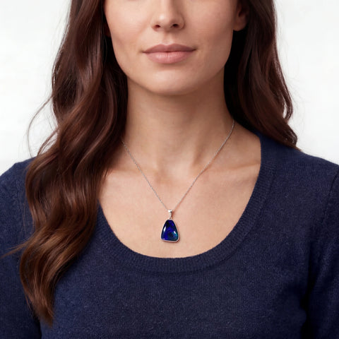 Woman wearing a necklace with a blue pendant on a plain background