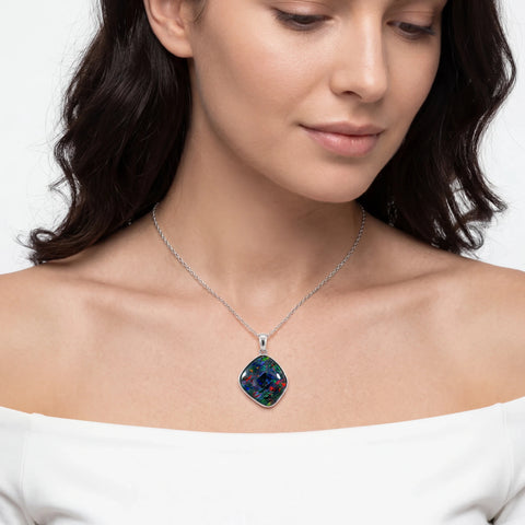 Woman wearing a necklace with a colourful pendant on a plain background