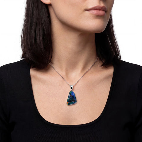 Necklace with a blue pendant worn by a person against a white background