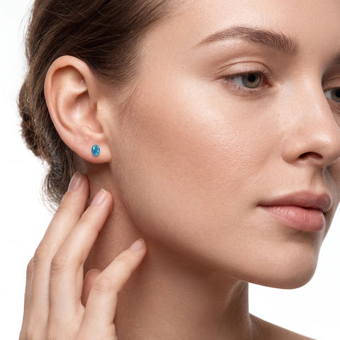 Close-up of a woman wearing a blue earring on a neutral background