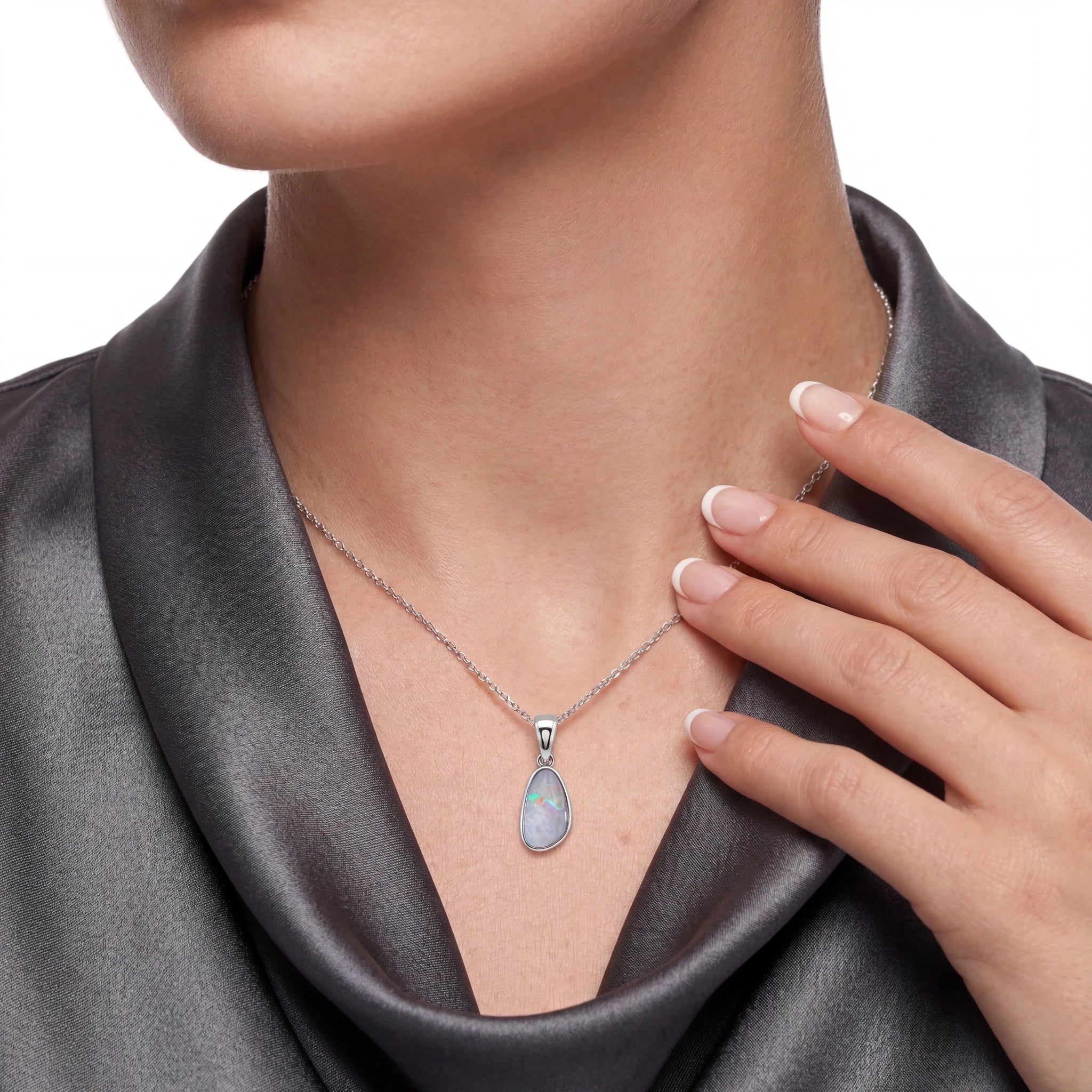 Necklace with a pendant worn by a person, hand touching the necklace.