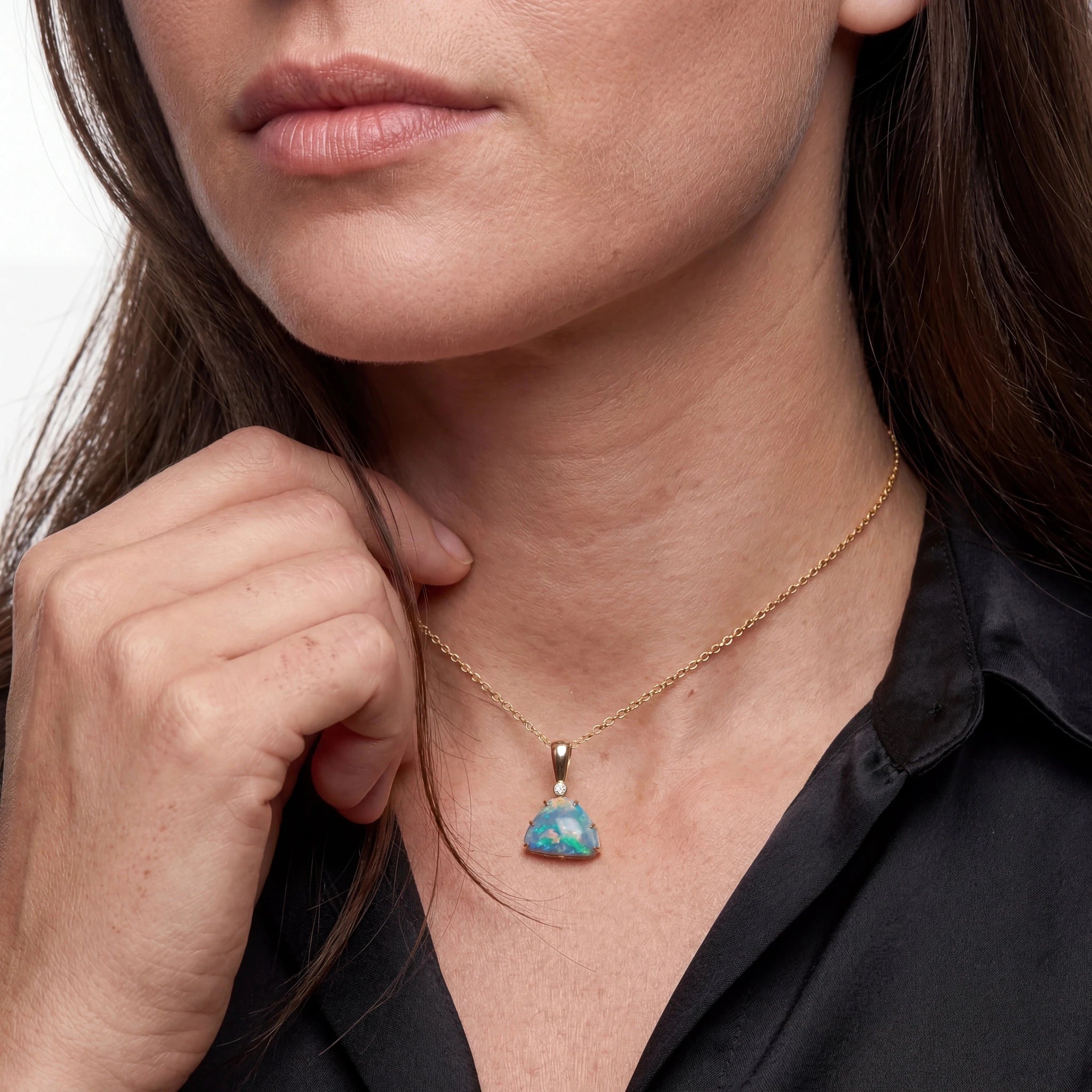 Close-up of a woman wearing a gold necklace with a turquoise opal pendant.