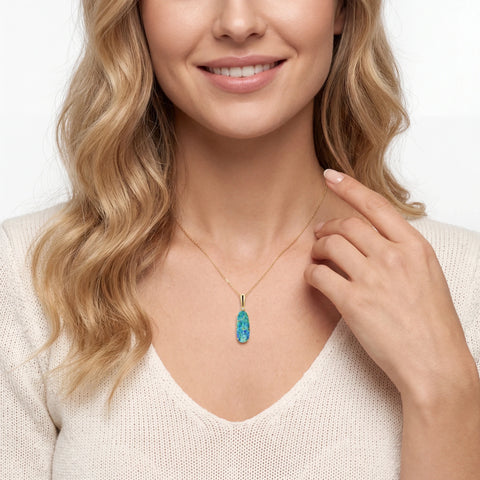 Woman wearing a necklace with a blue opal pendant against a white background