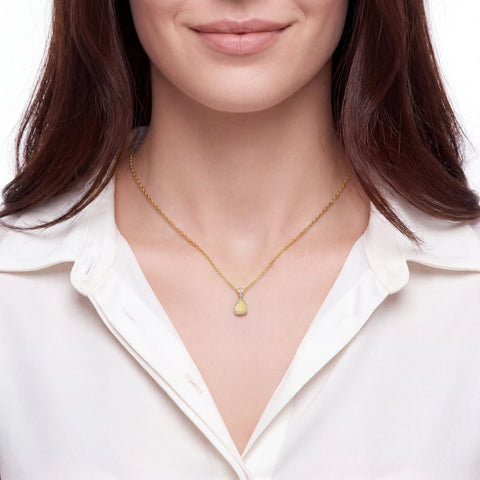 Woman wearing a gold necklace with a heart pendant on a white background