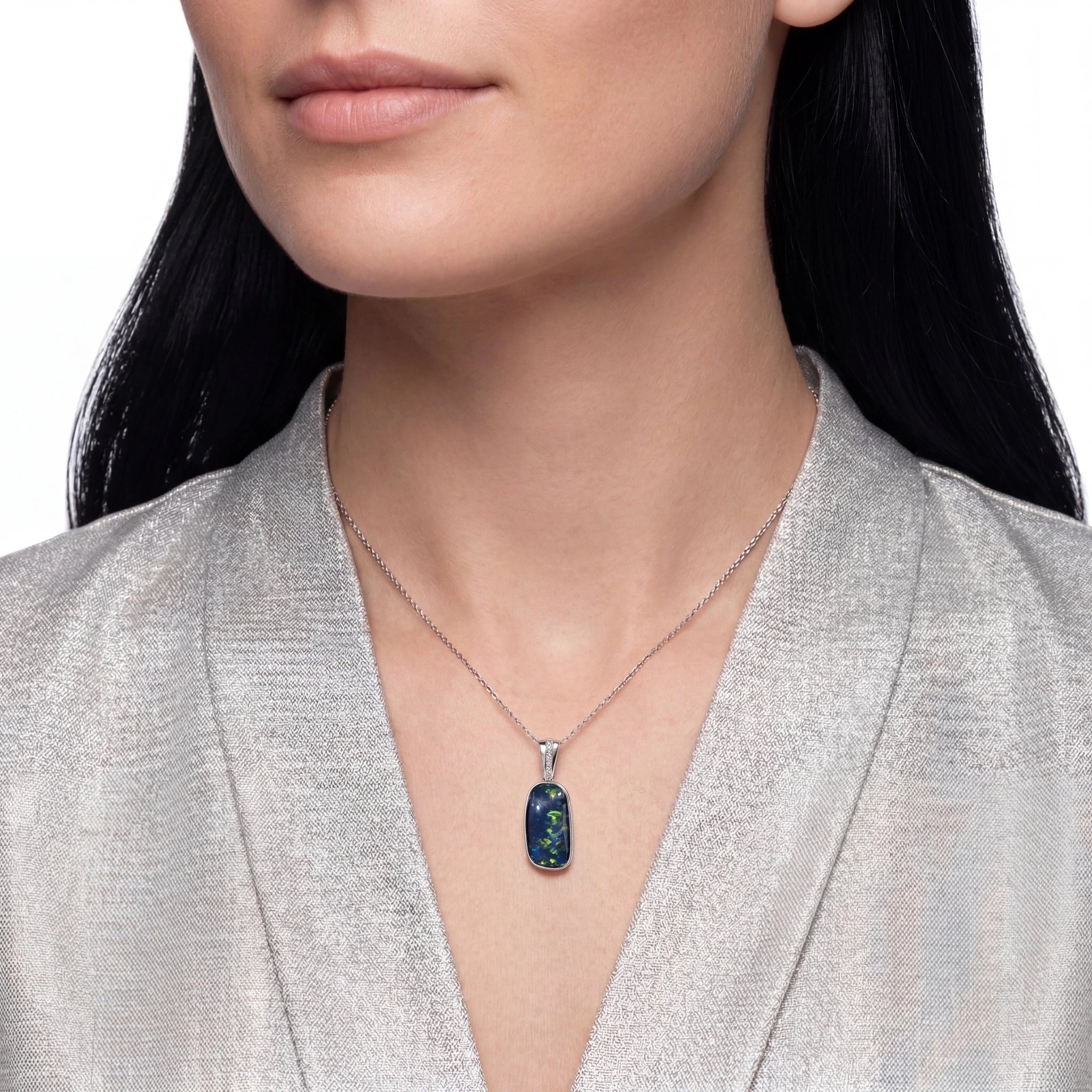 Woman wearing a silver necklace with a blue pendant against a neutral background