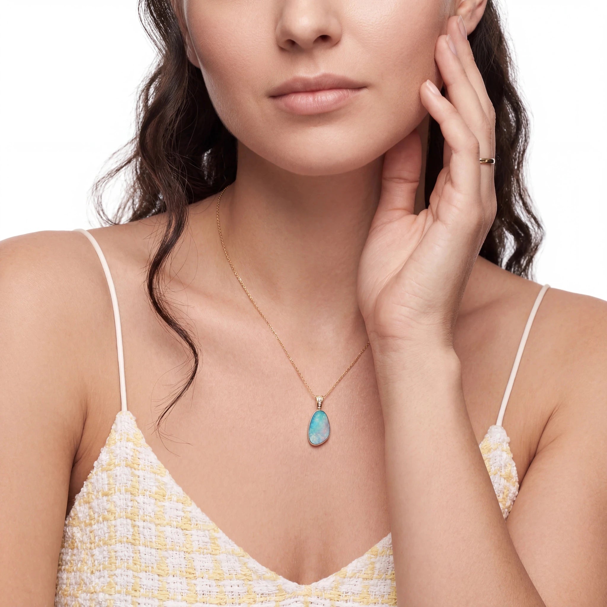 Woman wearing a gold necklace with a turquoise pendant on a white background