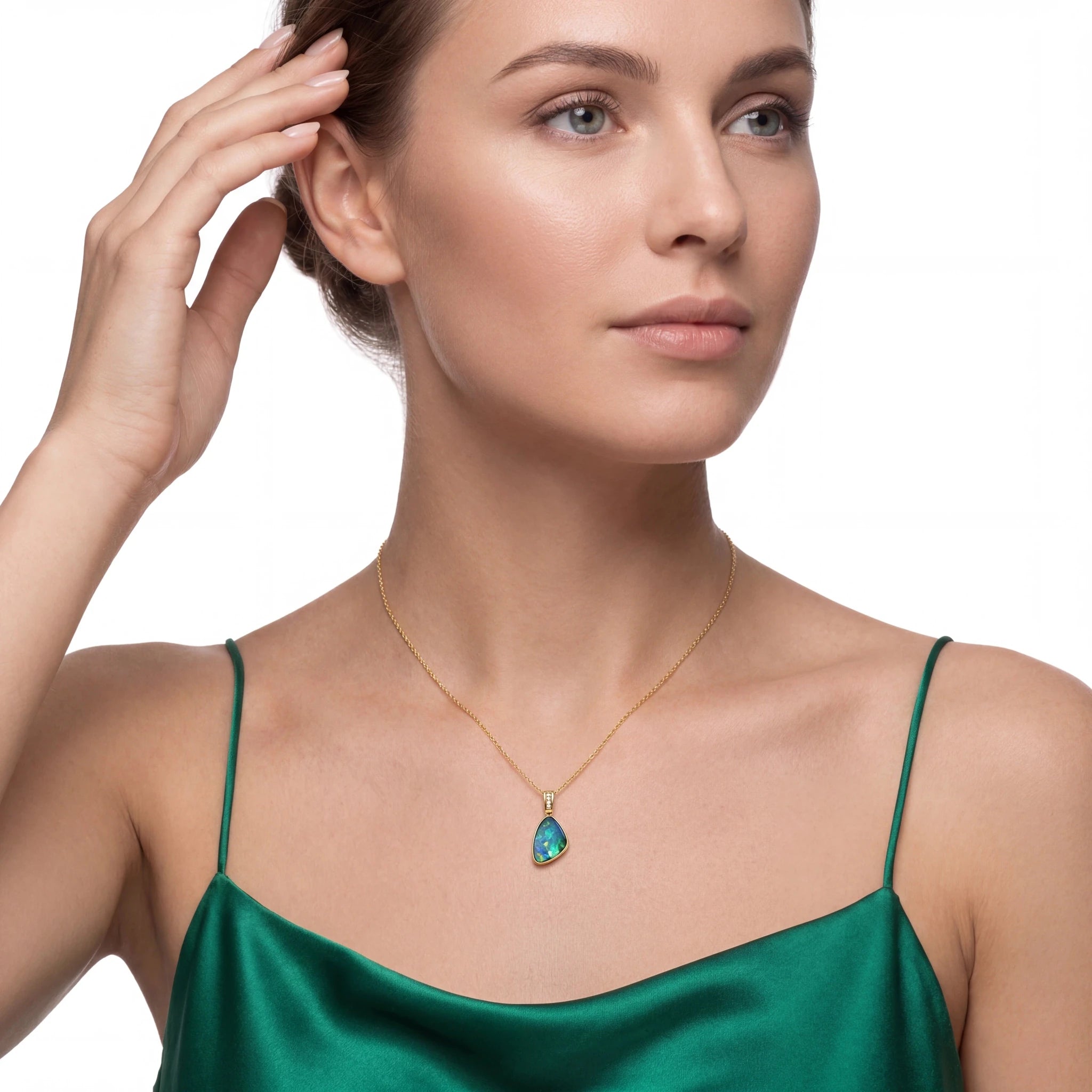 Woman wearing a gold necklace with a green pendant on a white background