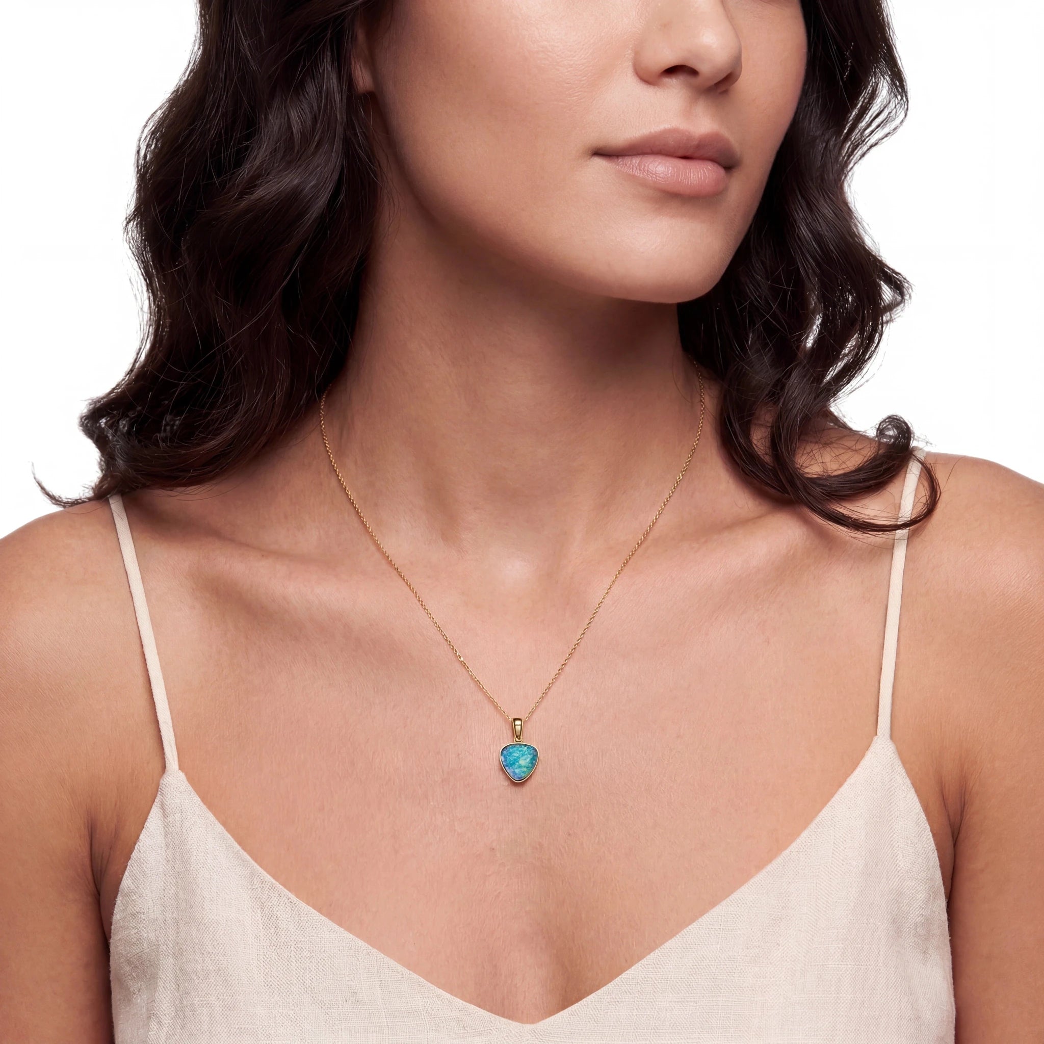 Woman wearing a necklace with a turquoise heart pendant on a plain background