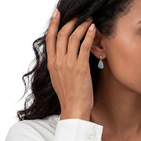 Woman wearing a blue opal earring with a white background