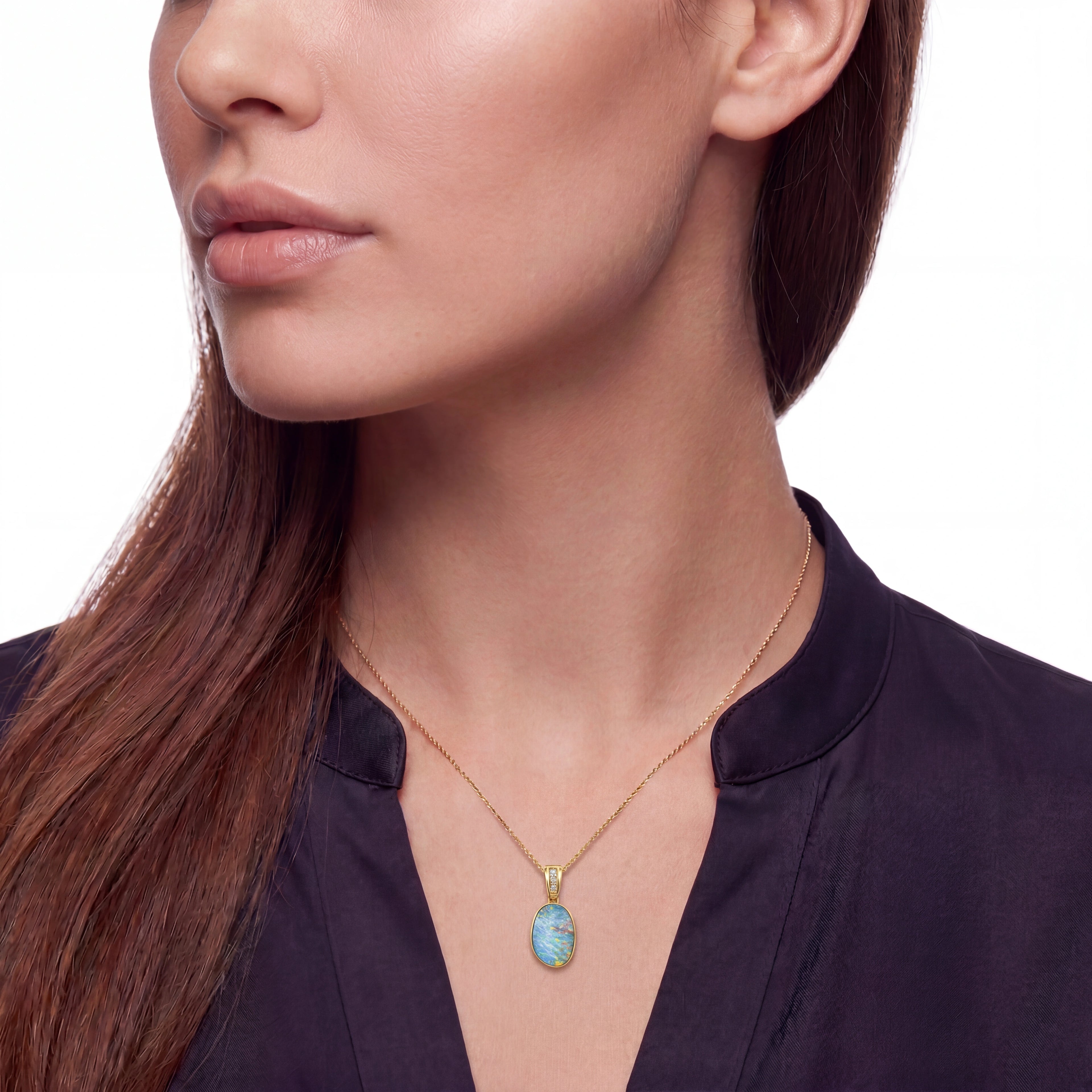 Close-up of a woman wearing a delicate gold chain necklace with an oval opal pendant featuring a light blue marbled pattern, set against a clean white background.