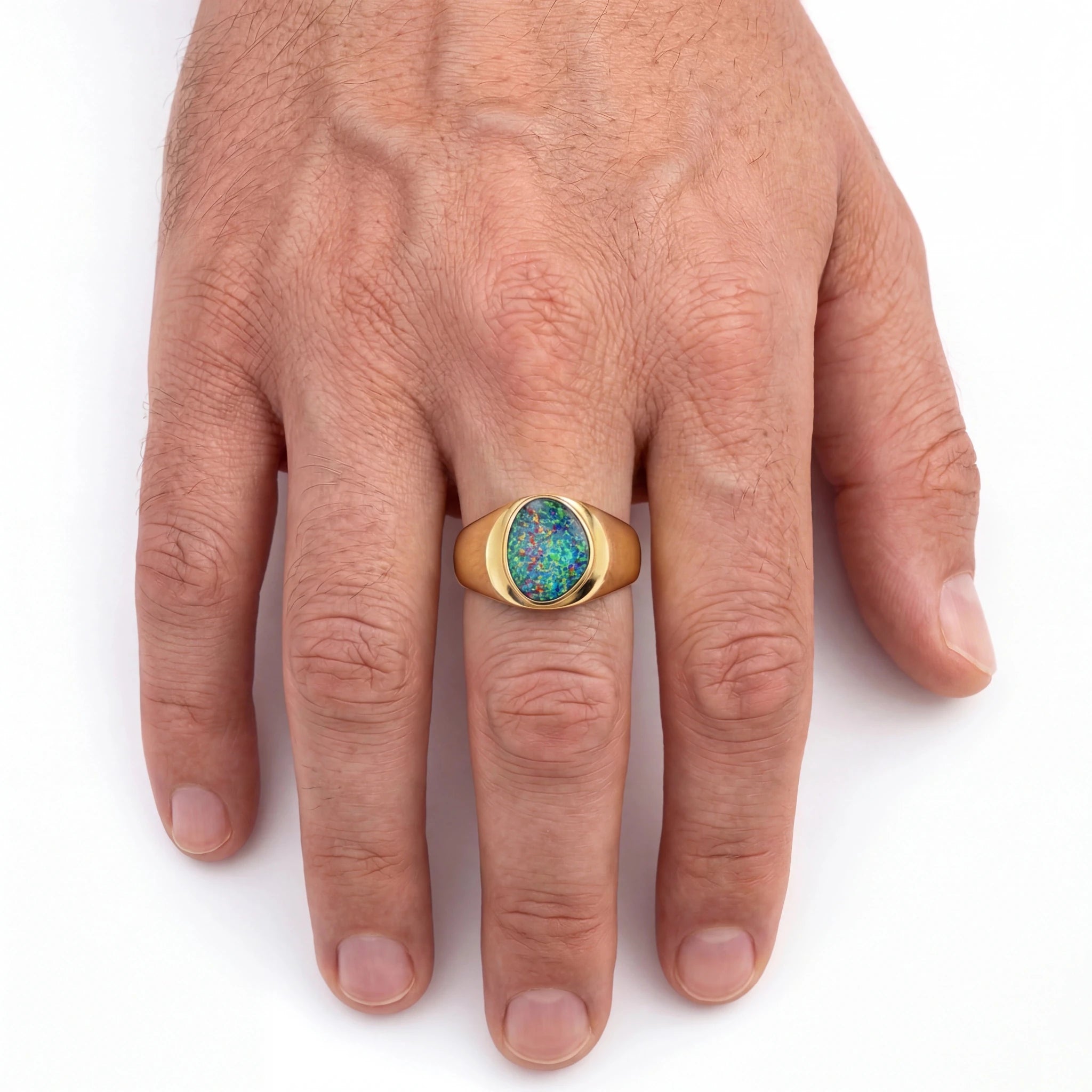Gold ring with a colourful gemstone on a person's finger against a white background