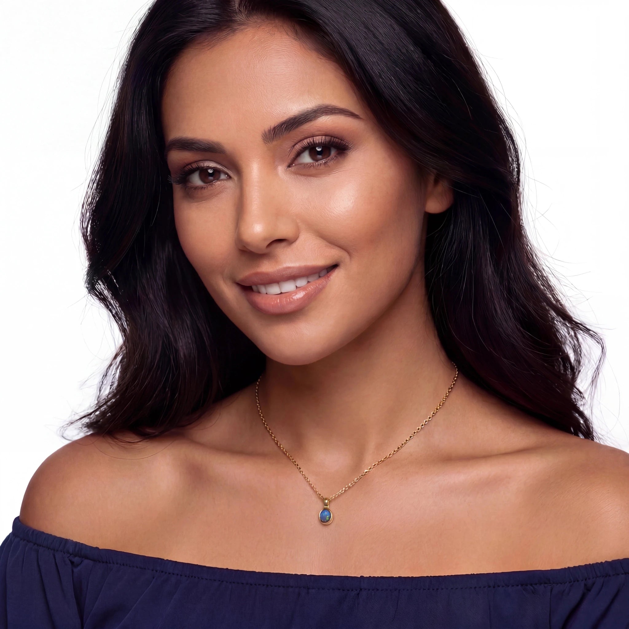 Woman wearing a blue off-shoulder top and gold necklace with a blue pendant on a white background