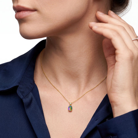 Close-up of a woman wearing a gold necklace with a colorful pendant.