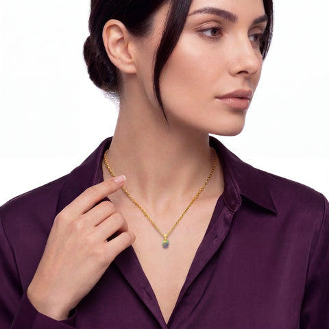Woman wearing a gold necklace with a purple shirt on a white background