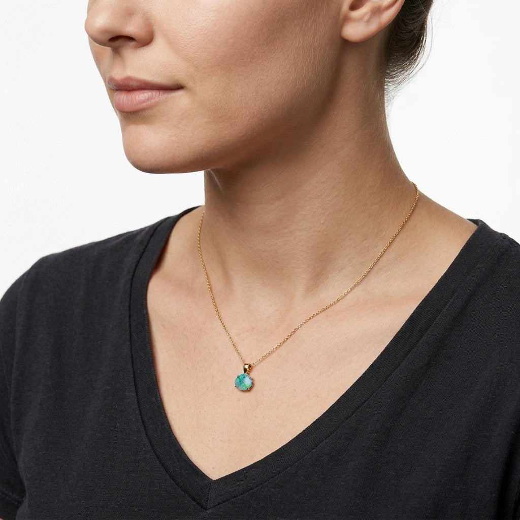 Woman wearing a gold necklace with a turquoise opal pendant on a white background