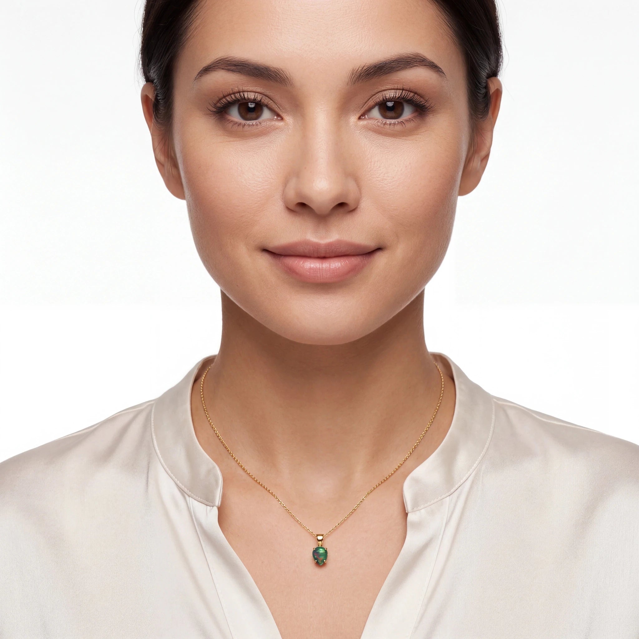 Woman wearing a gold necklace with a green opal pendant on a white background