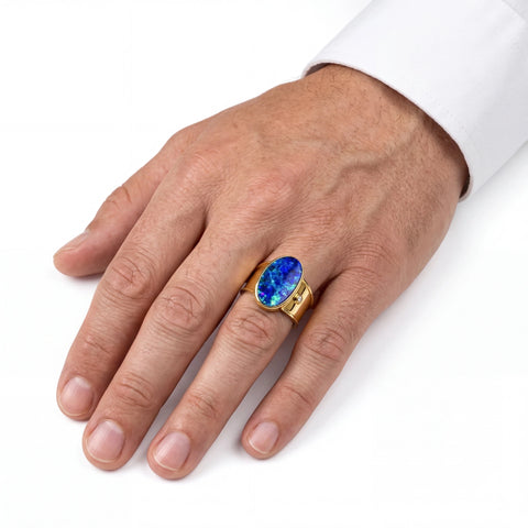Man wearing a gold ring with a blue gemstone on a white background