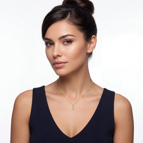 Woman wearing a gold necklace with a green pendant on a white background