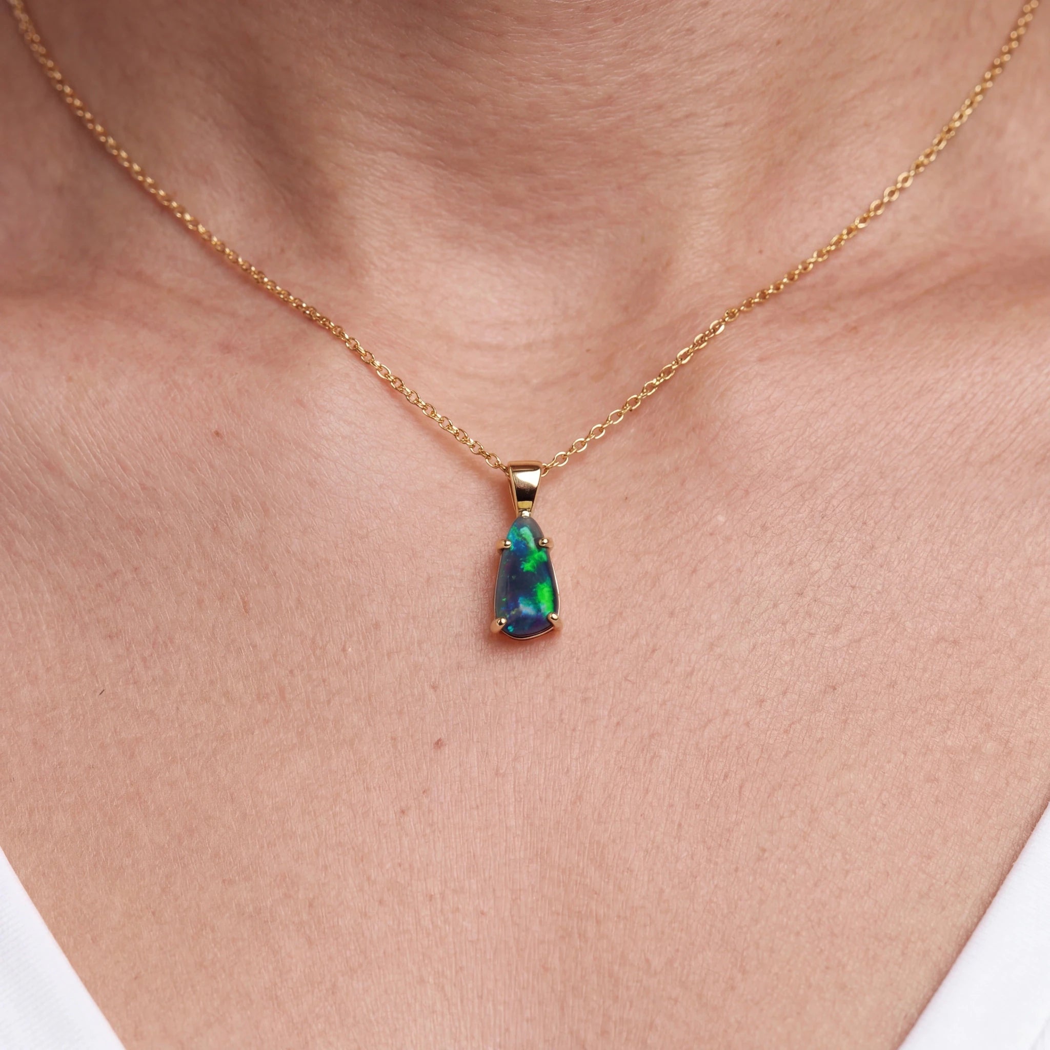 Opal pendant necklace on a gold chain worn by a person