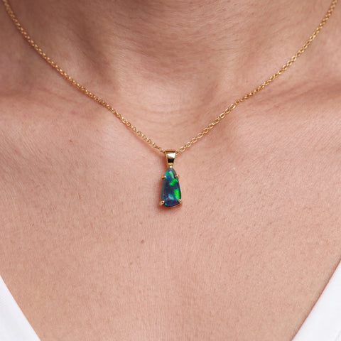Opal pendant necklace on a gold chain worn by a person