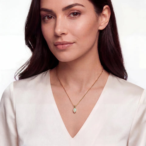 Woman wearing a gold necklace with a pendant on a white background