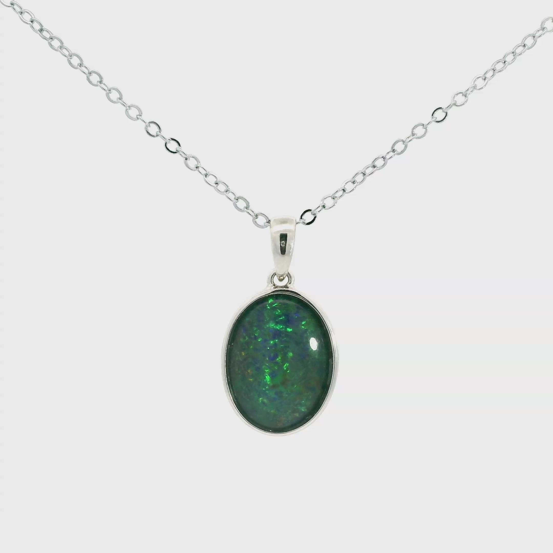 Video of a Silver pendant with a green stone on a white background