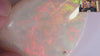 Video of a Teardrop-shaped opal stone with a vibrant play of colours on a white background