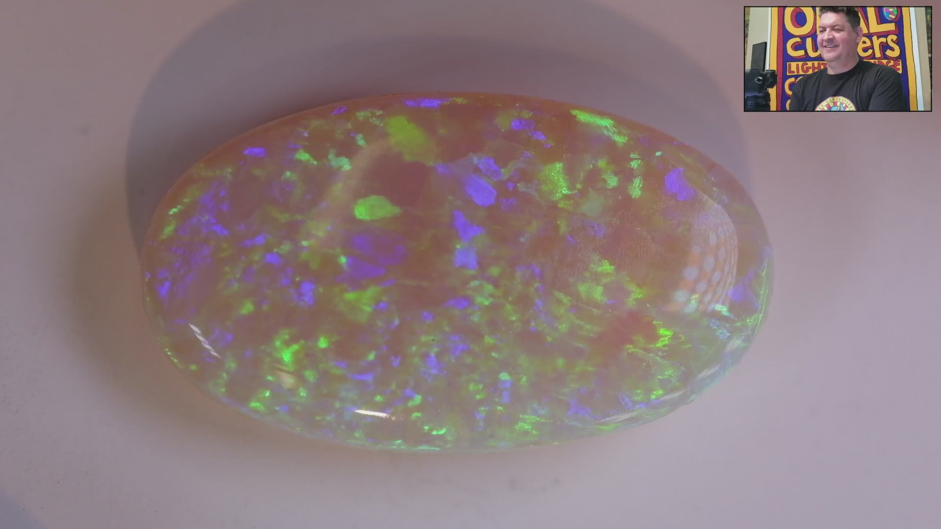 Video of an Opal stone with multicoloured fluorescence on a white background