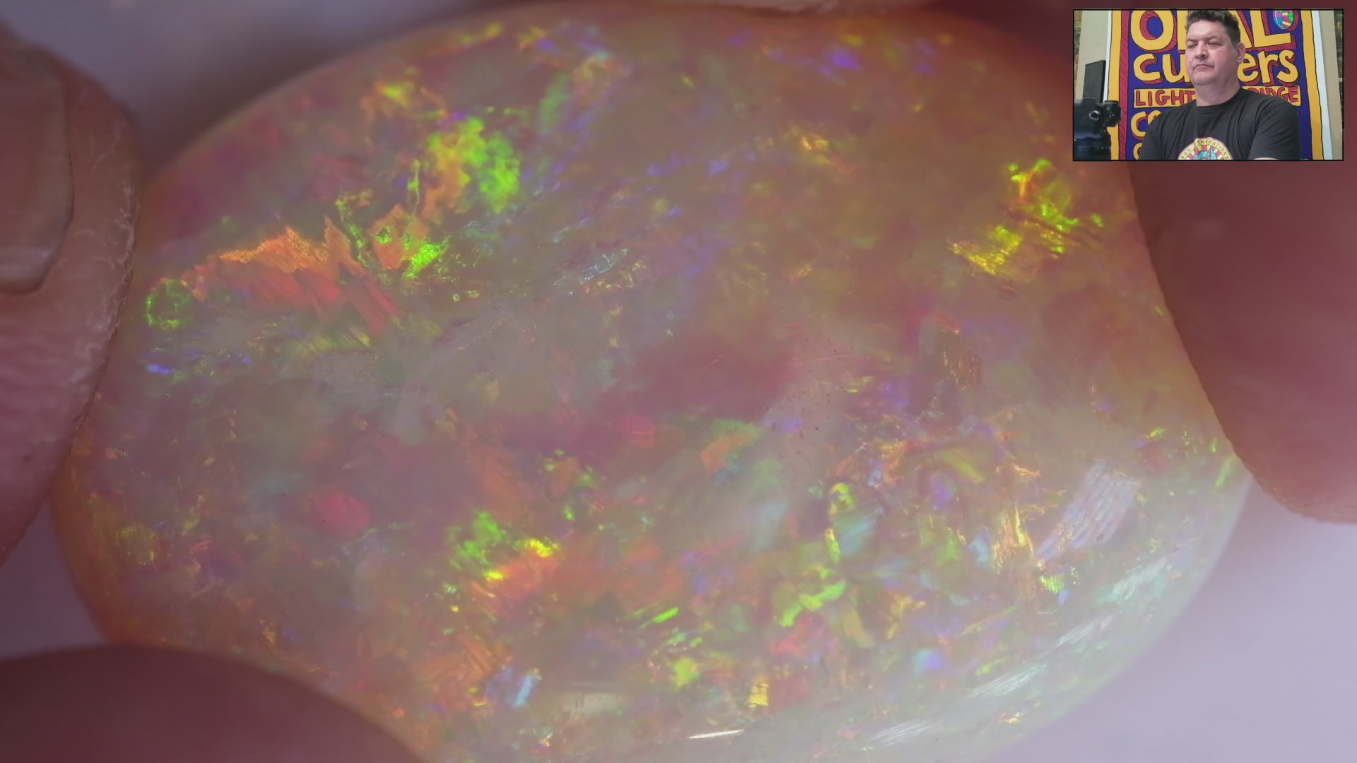 Video of an Opal stone with green and yellow hues on a white background