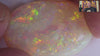 Video of an Opal stone with green and yellow hues on a white background