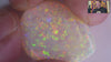 Video of an Opal stone with multicolour play of light on a white background