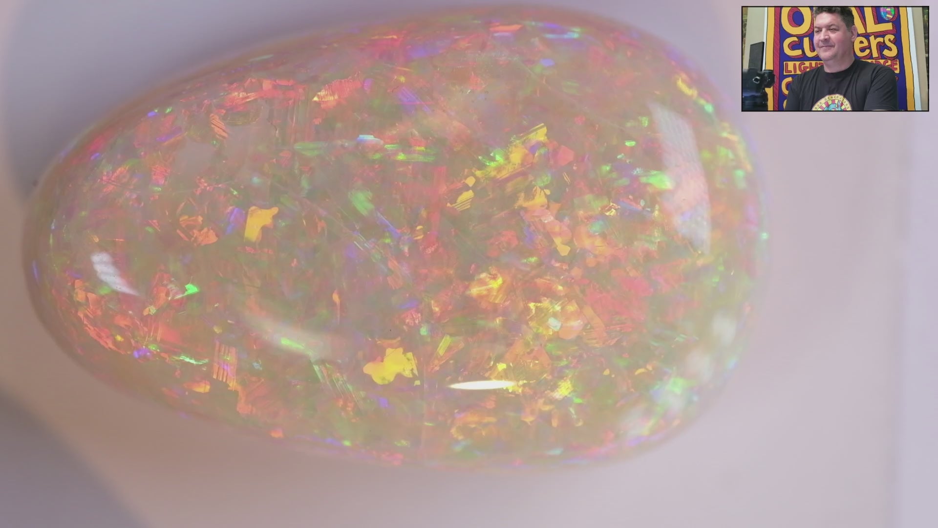Video of an Opal stone with multicoloured fluorescence on a white background