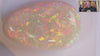 Video of an Opal stone with multicoloured fluorescence on a white background