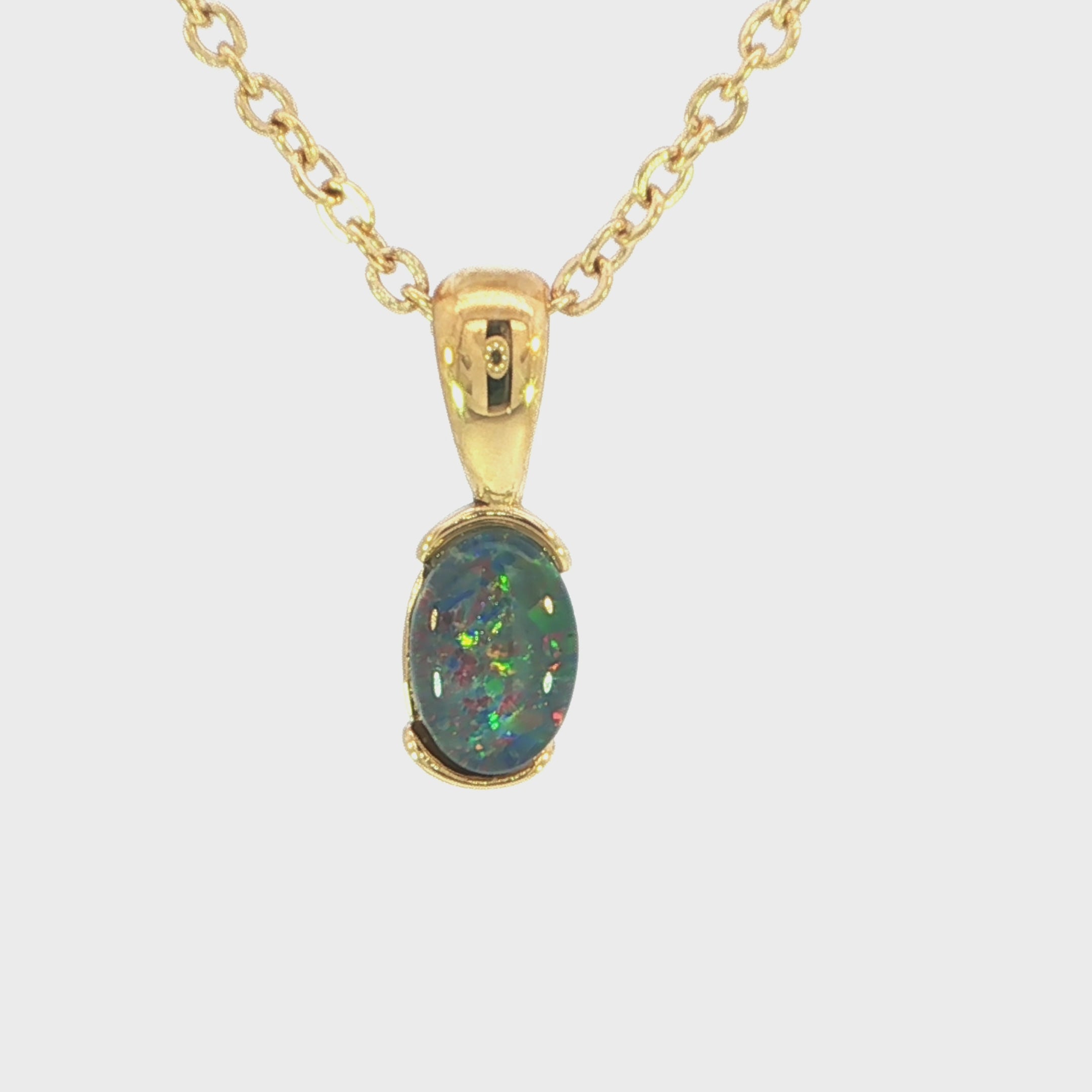Video of a Gold pendant with a colourful opal gemstone on a white background