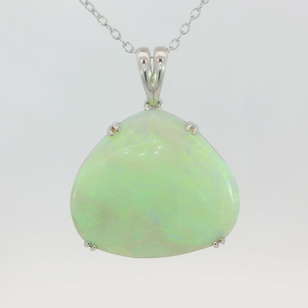 Video of a silver pendant necklace featuring a teardrop-shaped iridescent white opal gemstone with green and blue flashes, set in a polished silver bezel on a matching silver chain