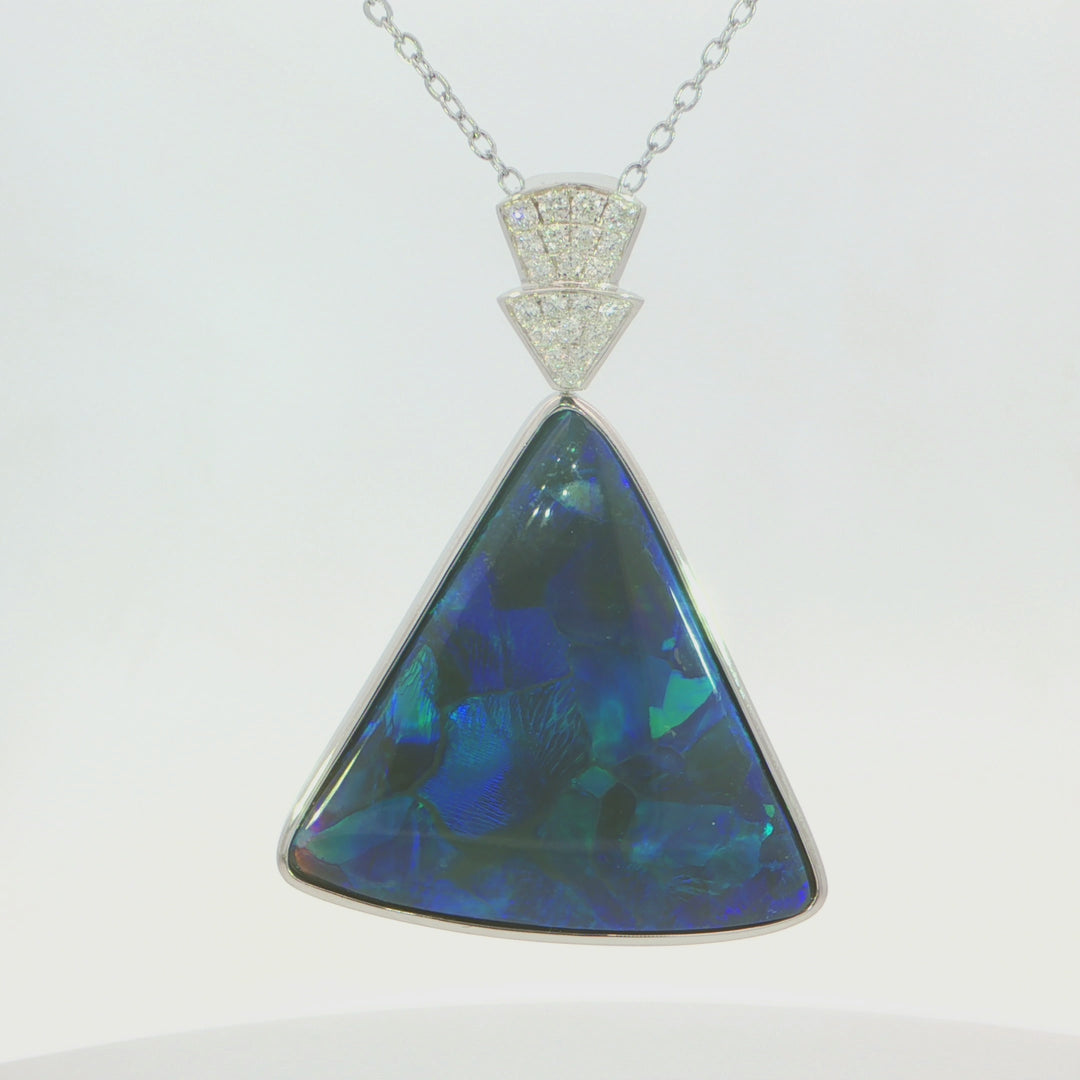 Video of a silver pendant necklace featuring a large, faceted triangular opal gemstone with vibrant blue and green play-of-colour, set in a silver bezel with a pavé diamond cap on a delicate silver chain.