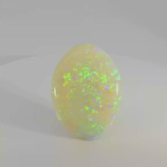 Video of an Opal stone with green and purple speckles on a white background